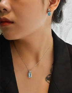 Detail view of emerald cut aquamarine jewelry set with X-shaped diamond accents