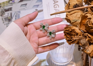 Macro detail of emerald bow knot stud earrings featuring micro-pave white crystals
