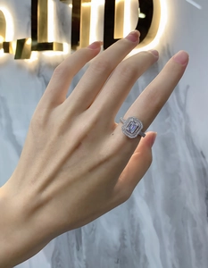 Close-up of emerald-cut rectangular gemstone ring with double halo pavé setting