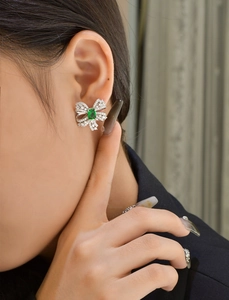 Detail of sterling silver emerald bow earring with micro-paved zircons on a model's ear
