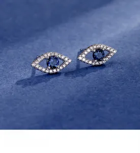 Macro shot of S925 sterling silver evil eye stud earrings with blue gemstone and pavé diamonds