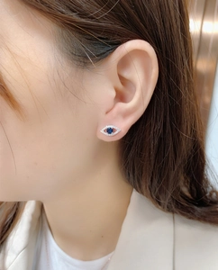Detail of S925 silver evil eye stud earring with blue sapphire stone on a model