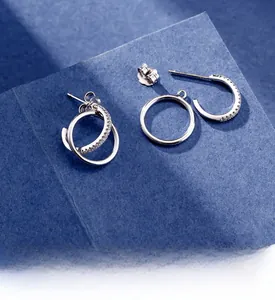 Macro detail of silver double ring earrings with polished platinum finish on blue fabric