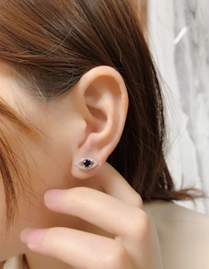 Close-up of S925 silver evil eye stud earrings with blue sapphire and crystal accents