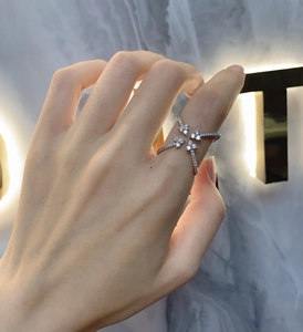 Detail of four-prong silver ring with butterfly floral pattern and pavé zircons on hand