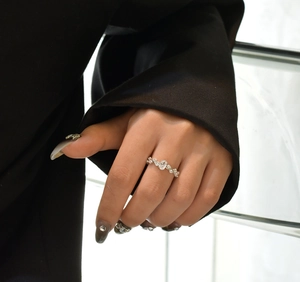 Close-up of vine-like silver ring with marquise and round stones on a model's hand