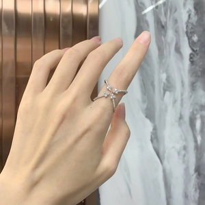 Detailed view of criss-cross sterling silver ring with pavé cubic zirconia stones on finger