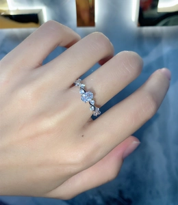Detailed macro of oval cut diamond ring with wave shaped band on woman finger