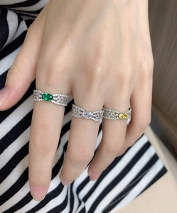 Primer plano de anillos de plata S925 con esmeralda y circón en los dedos del modelo