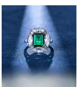 Macro detail of emerald-cut green gemstone ring with marquise diamonds in platinum finish