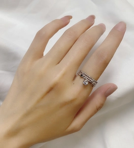 Close-up of triple-layered silver chain ring with round zircon pendant on a finger