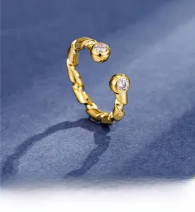 Detail of gold twisted rope ring with clear round zircons on blue textured background