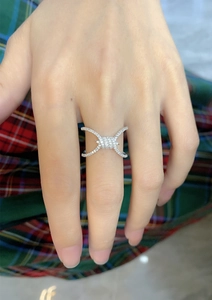 Detail of silver knot ring with pavé cubic zirconia worn on finger over plaid fabric
