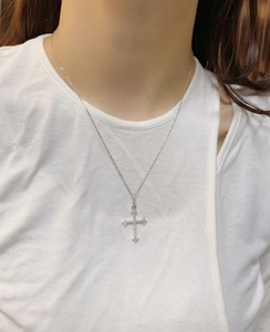 Detailed close-up of a sterling silver cross necklace with pavé zircons on a model
