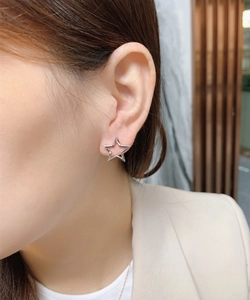 Close-up of minimalist S925 sterling silver star earrings on model with beige suit