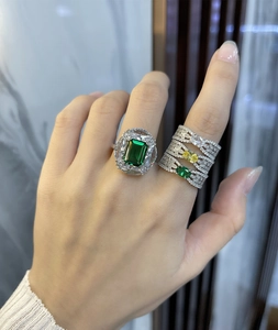 Detailed view of emerald-cut green gemstone ring with three matching diamond bands