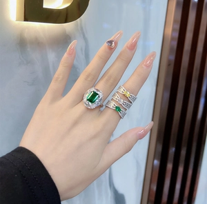 Detail view of emerald cut green gemstone ring with stacked sparkling bands on a hand
