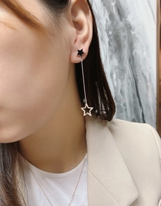 Detail of asymmetric tassel star earrings on model showing S925 silver and black stars