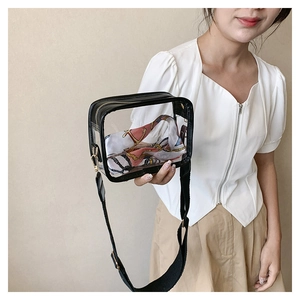 Close-up of clear PVC crossbody bag with black trim and colorful scarf inside