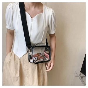 Detail of transparent PVC crossbody bag with wide shoulder strap and pink scarf accent