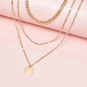 Three-layer gold chain necklace featuring curb chain and minimalist round disc pendant