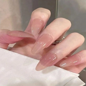 Macro view of elegant long almond press-on nails with a glossy nude pink finish