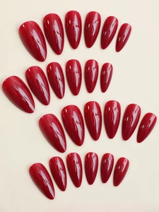 Detail view of glossy burgundy almond-shaped press-on nails neatly arranged on background