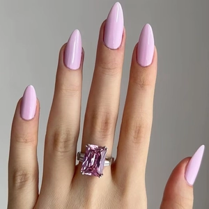 Detailed view of long almond-shaped glossy light pink press-on nails on a hand with ring