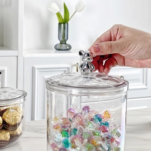 Transparent plastic storage jar with a silver bear handle lid filled with colorful candies