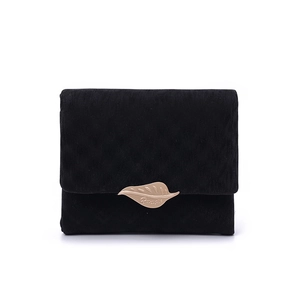Close-up of black corduroy wallet featuring a gold leaf metal buckle and fine texture