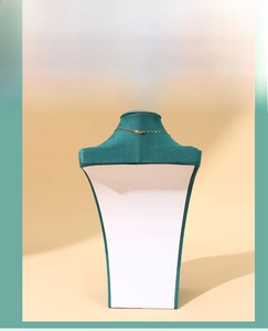 Detailed view of dark green fabric necklace display stand with white curved support base
