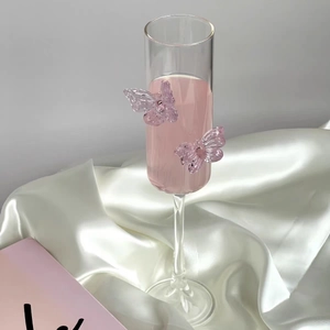 Detail of a flute champagne glass with lavender butterfly accents on white silk