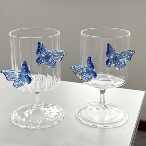 Close-up of elegant clear glass cups featuring unique blue 3D butterfly decorations