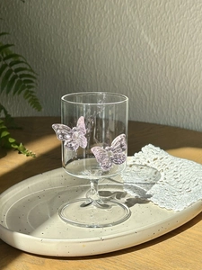 Detailed close-up of clear glass with two delicate pink 3D butterflies and lace texture