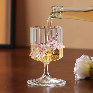 Macro detail of vertical textured glass stemware with 3D pink butterflies and liquid pour