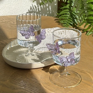 Detailed view of high borosilicate glass with 3D purple butterfly on wood surface