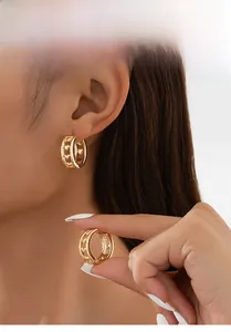 Gros plan de boucles d'oreilles créoles cœur dorées portées montrant la texture du métal