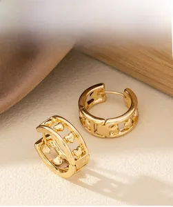 Détail de boucles d'oreilles créoles dorées avec motifs cœurs sur soie et bois