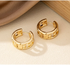 Détail des boucles d'oreilles créoles dorées avec motifs de cœurs évidés