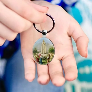 Our Lady of Fatima religious keychain with silver oval pendant held in hand