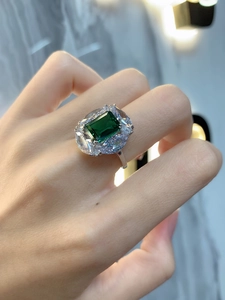 Detail of luxury emerald cut ring with sparkling marquise halo stones on model hand