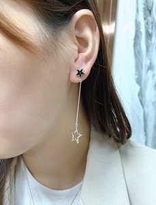 Detail of asymmetric tassel star earrings with silver hollow star charm on model