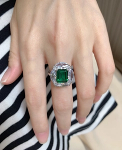 Detail of emerald cut green stone ring with teardrop zirconia on silver band