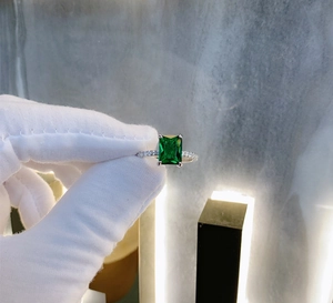 Macro shot of a 925 silver ring featuring an emerald-cut green gemstone and side diamonds
