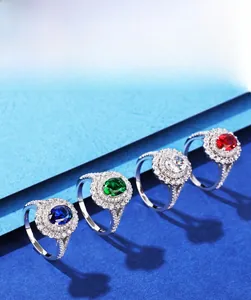 Détail de bagues halo ovales en zircon bleu, vert, blanc et rouge serties sur argent 925