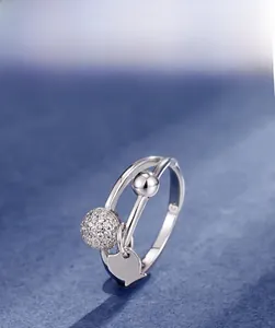 Detail of S925 sterling silver double ring with dangling heart pendant and cubic zirconia ball