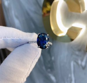 Detailed close-up of S925 silver ring with 9x12mm oval blue stone and pavé zircon band