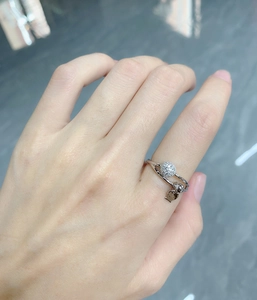 Detail of 925 sterling silver ring with small diamond ball and heart-shaped pendant on finger