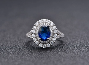 Vue macro d'une bague ovale avec pierre bleue et double entourage de diamants blancs