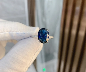 Detailed macro view of an oval blue gemstone ring with micro-pave diamond band